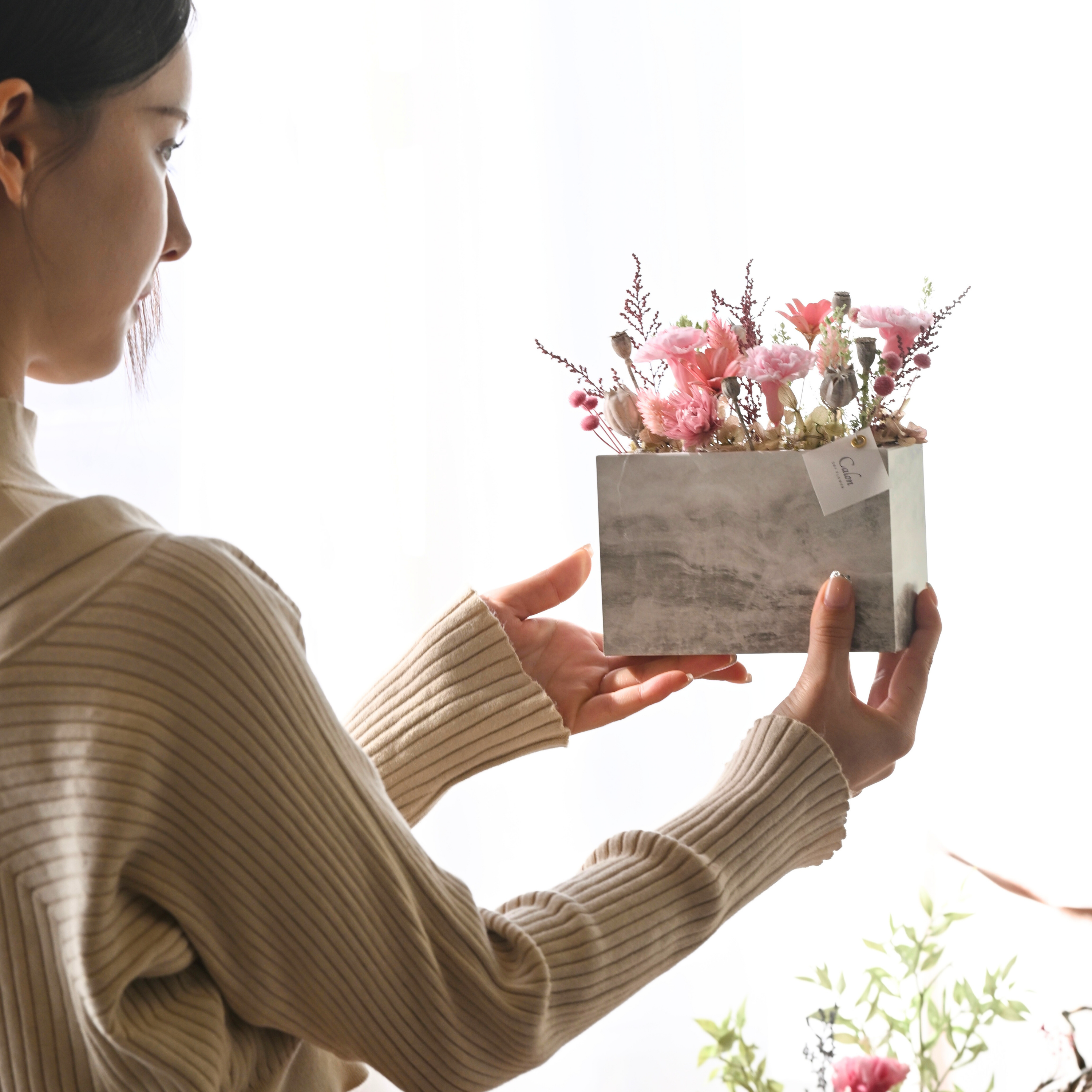 Calon DRY FLOWER母の日ギフト2026『プリザーブドカーネーションのストーン調置き型アレンジ』ピンクをモデルが手で持っている画像